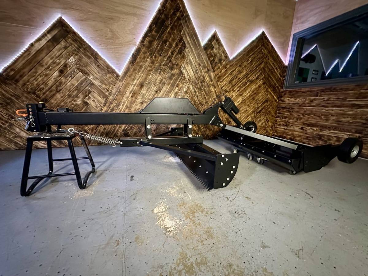 Snow Groomer Pro side view on showroom floor with mountain wood backdrop